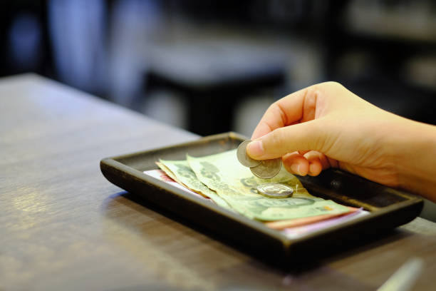 explotación de la mano del primer plano de bill con tailandés dinero billetes y monedas (punta) en el recibo de dinero en efectivo cambio del restaurante - dinner currency table business fotografías e imágenes de stock