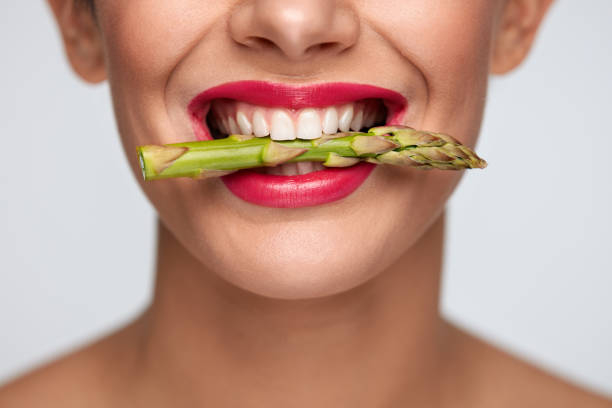 Healthy Diet. Beautiful Woman Mouth Holding Fresh Asparagus Healthy Eating. Closeup Of Woman Mouth With Beautiful Pink Lips Makeup Holding Fresh Asparagus Between White Teeth. Smiling Female Face With Vegetable In Mouth. Diet Food Concept. High Resolution eating asparagus stock pictures, royalty-free photos & images