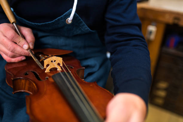 artigiano che ripara un violino antico - workshop old fashioned old instrument maker foto e immagini stock