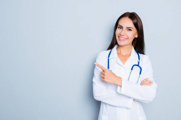 istock Smiling happy doctor pointing with finger on blue background 949552678