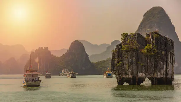 Beautiful sunset Tourist junks floating among limestone rocks at Ha Long Bay, South China Sea, Vietnam, Southeast Asia.