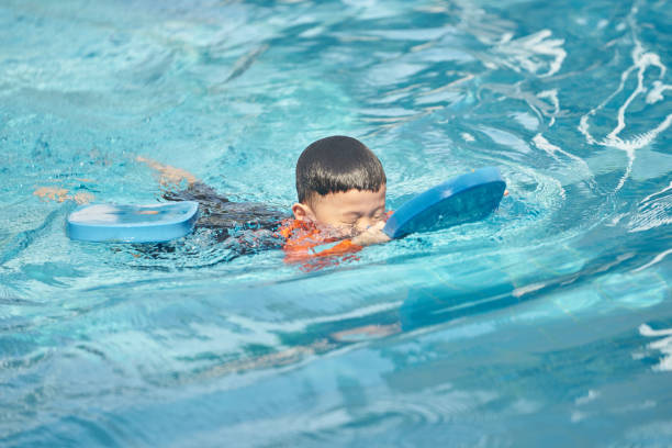 istock boy practise swimming with foam pad floater in water 949553828