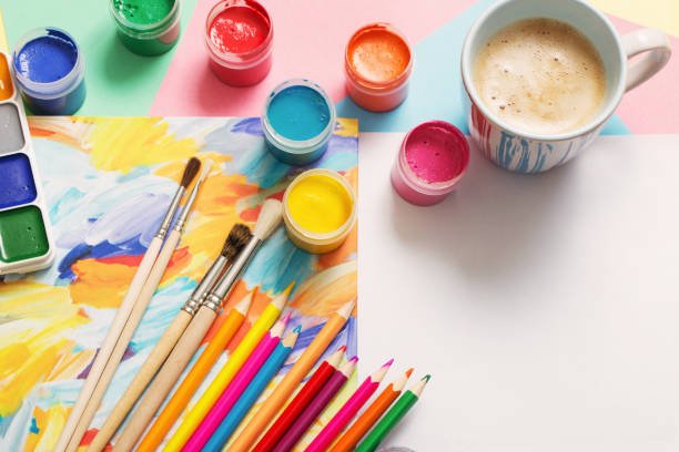 istock cup of coffee and paints, pencils on white background 949561250
