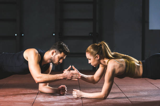 istock Young athletes giving high five to each other while doing push ups in sports hall 949561362