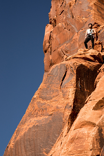 Proud female athlete at the top of her climb standing looking out over the vast landscape view she can see after a great climb