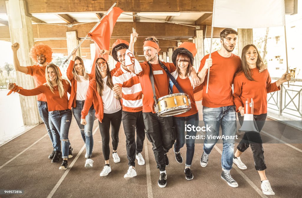 Football supporter fans friends cheering and walking to soccer cup match at intenational stadium - Young people group with red and white t-shirts having excited fun on sport world championship concept Fan - Enthusiast Stock Photo