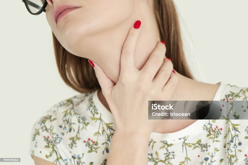 Young woman holding her throat, Sore throat, Sore throat, Young woman holding her throat, studio shot Hypothyroidism Stock Photo