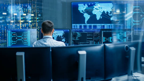 Back View in the System Control Center Operator Working. Multiple Screens Showing Technical Data. Back View in the System Control Center Operator Working. Multiple Screens Showing Technical Data. surveillance stock pictures, royalty-free photos & images