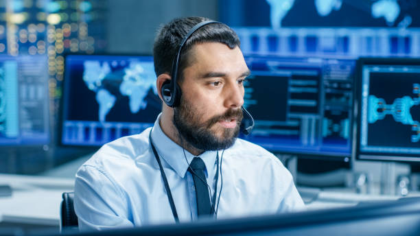 istock System Control Room Dispatcher Talks into Headset. He Controls Correct Work of the Facility. In the Background Multiple Monitors Show Technical Data. 949580986