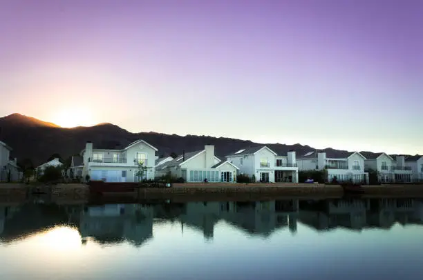 A row of houses surrounding a lake filled with reflections of the houses at sunrise, Val de Vie, Cape Town, South Africa