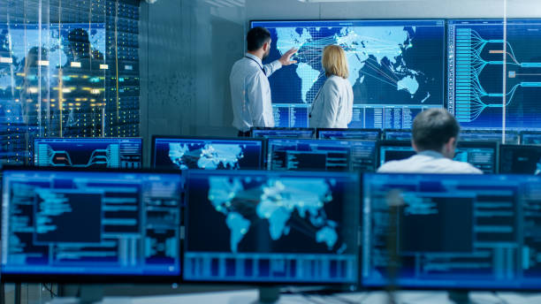 istock In the System Monitoring Room Two Senior Operators Work on a Big Interactive Map. Facility is Full of Screens Showing Technical Data. 949581032
