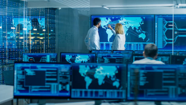 istock In the System Monitoring Room Two Senior Operators Work on a Big Interactive Map. Facility is Full of Screens Showing Technical Data. 949581038