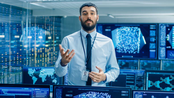 istock In the World's Top Machine Learning Facility Scientist Excitedly Describes Project He Works on. Background Shows Screens with Working Neural Network/ Artificial Intelligence. 949581070