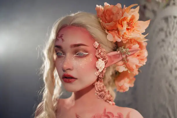 Young beautiful woman like the elf. Creative make-up and bodyart. Elvish ears, hairdo with flowers.