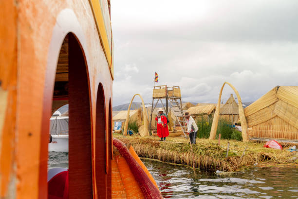 paar von native uro mit typischen trachten entlässt aus der küste einer schwimmenden insel totora, eines der typischen boote auf dem titicacasee - 6729 stock-fotos und bilder