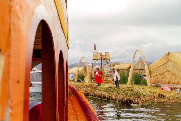 couple d’uros native avec des costumes typiques rejette de la côte d’une île flottante de totora à l’une des embarcations typiques sur le lac titicaca - 6729 photos et images de collection