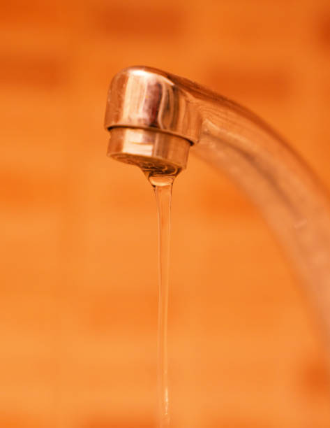 istock Water flowing from the tap in orange background, save water! 949595618