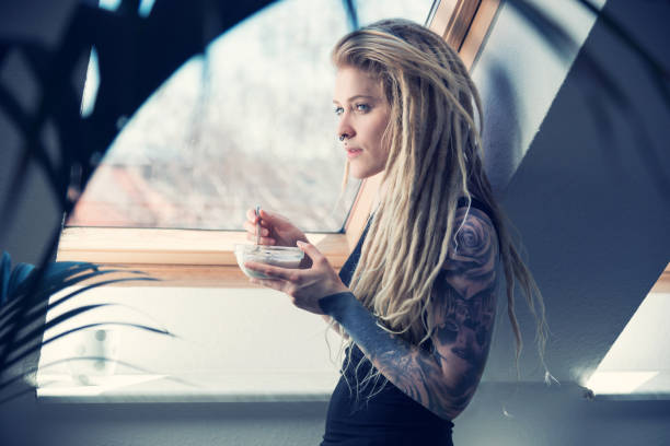 Young tattooed woman is taking her breakfast at home