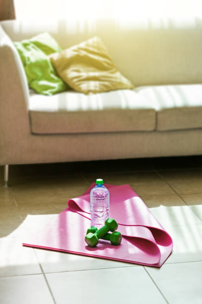 Two dumbbells with mineral water on yoga mat