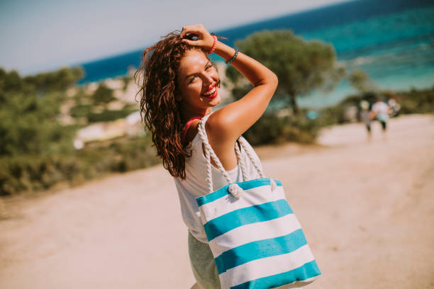 Pretty young woman with bag on the beach Pretty young woman with bag on the beach on a hot summer day beach bag stock pictures, royalty-free photos & images