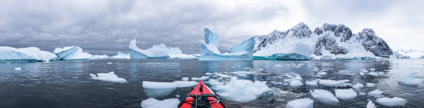 Panoramic view of kayaking in the Iceberg Graveyard in Antarctica Panoramic view of kayaking in the Iceberg Graveyard in Antarctica, incredible POV panorama with sea and ice, Antarctic Peninsula antarctic peninsula photos stock pictures, royalty-free photos & images