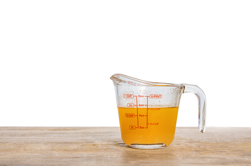 Orange juice in measuring cup isolated on white background