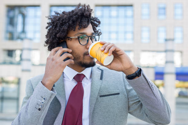 istock Handsome young businessman drinking coffee while talking on the phone 949614956