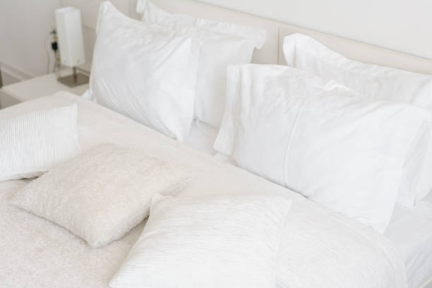 istock Comfortable soft pillows on the bed. Close-up white bedding sheets and pillow on light wall room background. Fresh bed concept 949623674