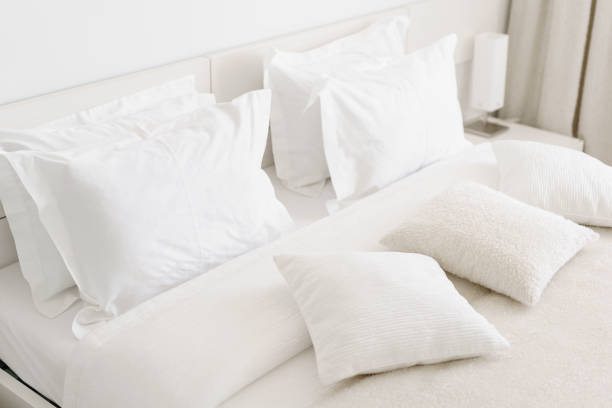 istock Comfortable soft pillows on the bed. Close-up white bedding sheets and pillow on light wall room background. Fresh bed concept 949623694