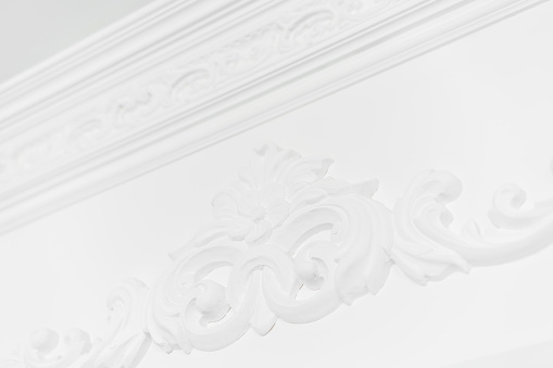 Stucco elements on white wall. Luxury design with mouldings. Beautiful ornate white decorative plaster in studio. Hotel room