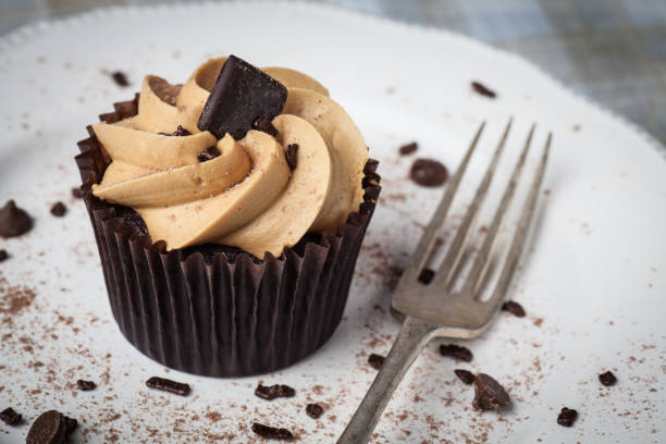 istock Salted Caramel cupcake on white plate with fork, dusted with cocoa powder and chocolate sprinkles 949627272