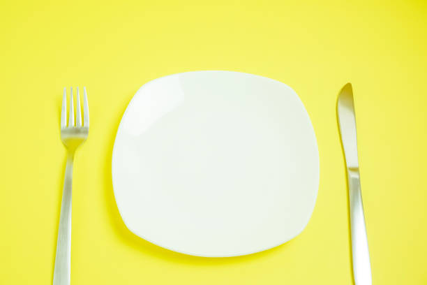 istock a dish and a knife and a fork. yellow background. 949657988