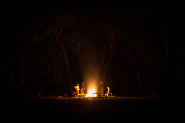 A fire sits in the centre with people crowding around it