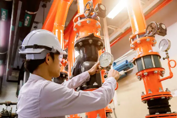 Photo of Engineer checking Condenser Water pump and pressure gauge , chiller water pump with pressure gauge.System ready.