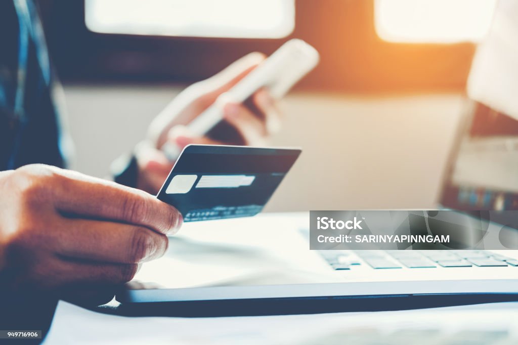 男を保持しているクレジット カードと携帯電話を使用保持ク��レジット カード ショッピングとオンライン - クレジットカードのロイヤリティフリーストックフォト