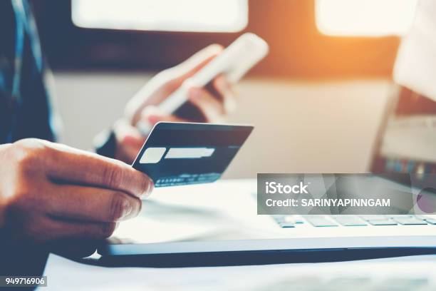 Man Holding Credit Card And Using Cell Phone Holding Credit Card With Shopping Online Stock Photo - Download Image Now