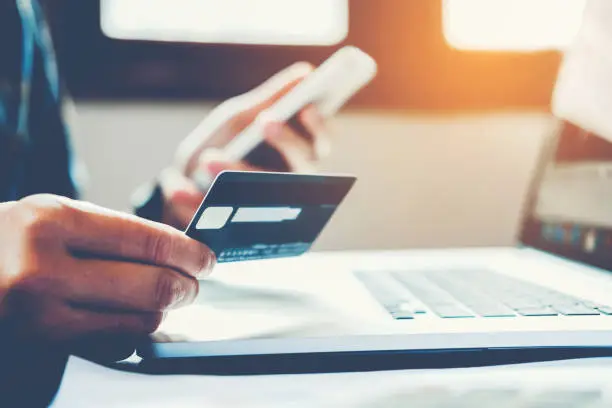 Photo of Man Holding Credit Card And Using Cell Phone holding credit card with shopping online