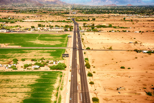 A state highway near Phoenix Arizona going through dried, arid, and unplanted farmland.