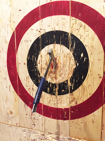 A large metal ax is embedded into a wooden target while playing the game of axe throwing.