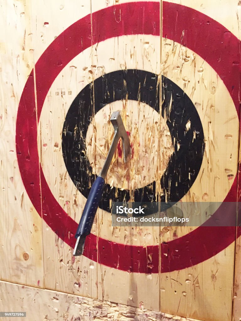 Axe Throwing at Targets A large metal ax is embedded into a wooden target while playing the game of axe throwing. Axe Throwing Stock Photo