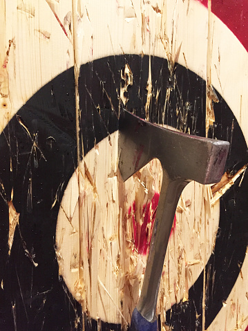 A large metal ax is embedded into a wooden target while playing the game of axe throwing.