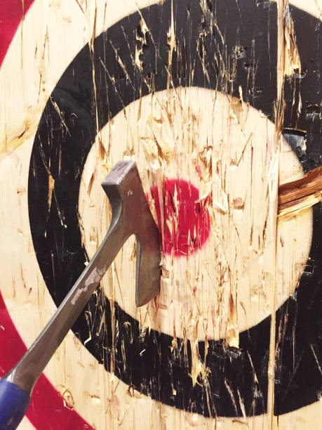 Axe Throwing at Targets A large metal ax is embedded into a wooden target while playing the game of axe throwing. axe photos stock pictures, royalty-free photos & images