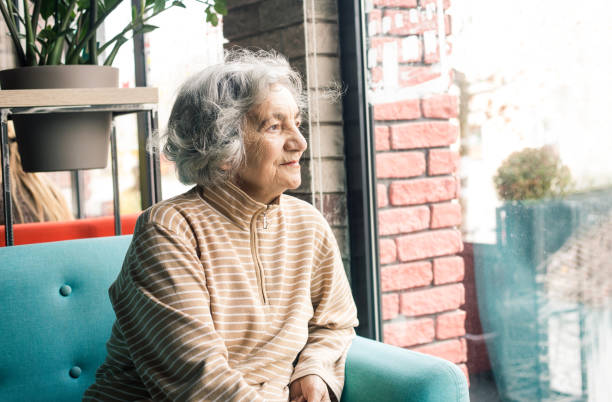 Senior woman looking through window stock photo