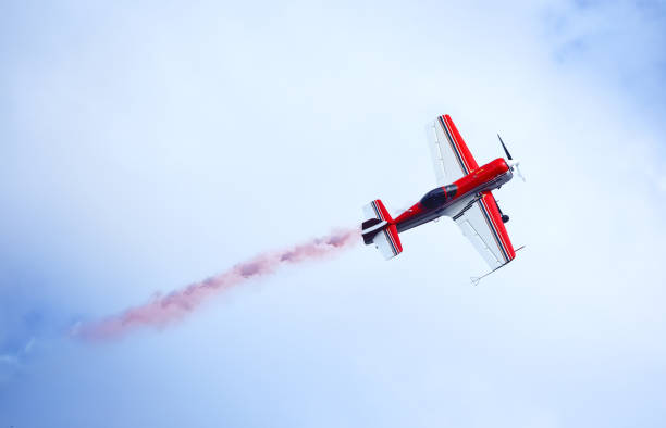 istock Red and white aircraft emitting colored smoke in the sky 949759088