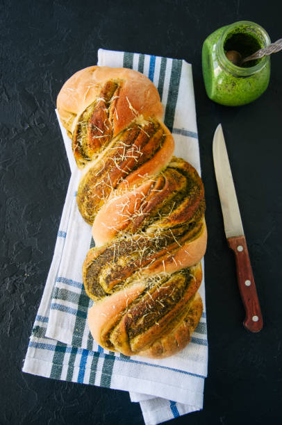istock Pesto braided bread on a napkin, black stone background. Top view. 949774898