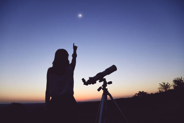 istock Young woman looking at the sky with a astronomical telescope. 949786766