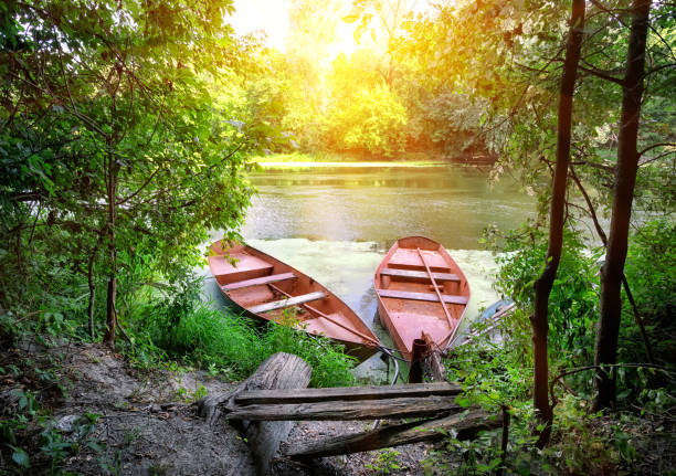Red boats on the river bank at the pier. Summer landscape. The concept of travel and recreation.