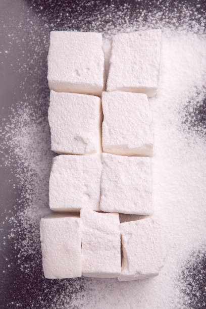istock Marshmallow cubes shugar powdered lying on black plate 949811970