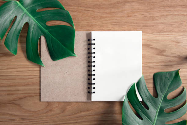 istock Blank open notebook page on wood background office desk with Tropical monstera leaves. Summer and spring concept. 949838530