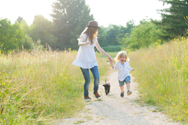 istock Little boy walking in park with his mother and puppy 949845708